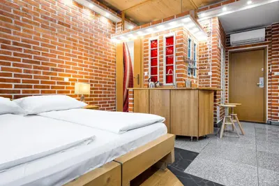 a room with two beds and a brick wall at Krowoderska Apartments in Kraków