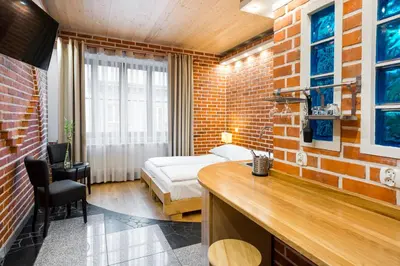 a bedroom with a bed and a brick wall at Krowoderska Apartments in Kraków