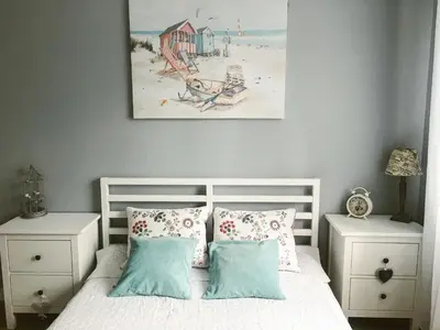 a bedroom with a white bed with pillows and a painting at Apartament LUSCINIA z 2 sypialniami in Kraków