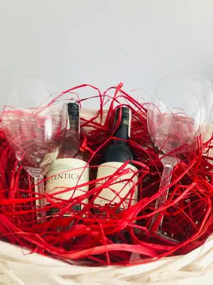 two bottles of wine in a basket with red yarn at Apartament LUSCINIA z 2 sypialniami in Kraków