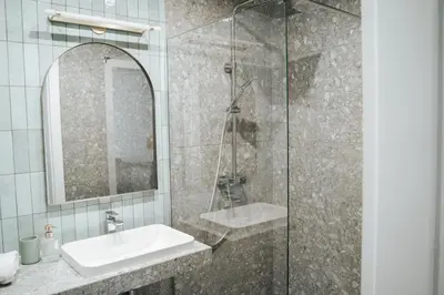 a bathroom with a shower with a sink and a mirror at Arkada Wadowice in Wadowice
