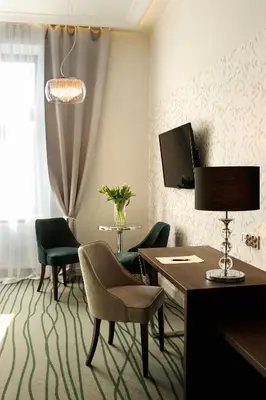 a living room with a table and green chairs at Plaza Boutique Hotel in Kraków