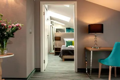 a hallway with a room with a bed and a desk at Plaza Boutique Hotel in Kraków
