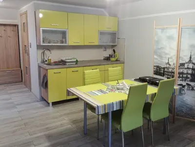 a kitchen with yellow cabinets and a table with green chairs at Michałowice Noclegi u Anety in Michałowice