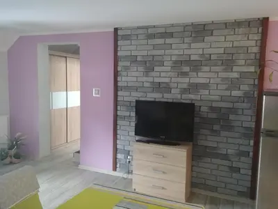 a living room with a tv on a brick wall at Michałowice Noclegi u Anety in Michałowice