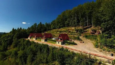 a snow covered hill with a house on a mountain at Domki Beskid in Rzyki