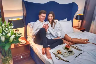 a man and a woman sitting on a bed at Shalom Kazimierz in Kraków