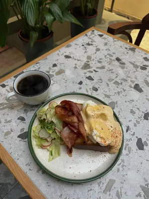 a plate with an egg and bacon and salad on a table at Shalom Kazimierz in Kraków