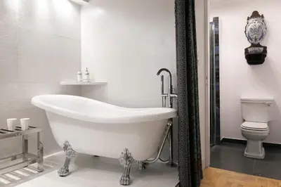 a bathroom with a white tub and a toilet at Orlowska Townhouse Apartments in Kraków