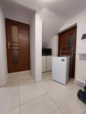 a small kitchen with a refrigerator and a door at Studio in Kraków