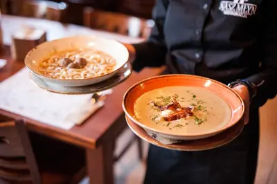 a person holding two bowls of soup on a table at Nasz Młyn in Sufczyn