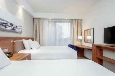 a bedroom with a bed and a blue chair at Hampton by Hilton Oswiecim in Oświęcim