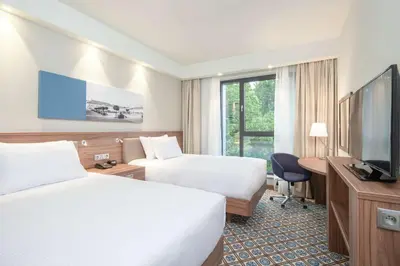 a hotel room with two beds and a flat screen tv at Hampton by Hilton Oswiecim in Oświęcim