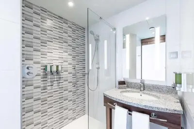 a white bathroom with a sink and a shower at Hampton by Hilton Oswiecim in Oświęcim