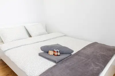 a white bed with two pillows and a blanket at Apartamenty Lea in Kraków