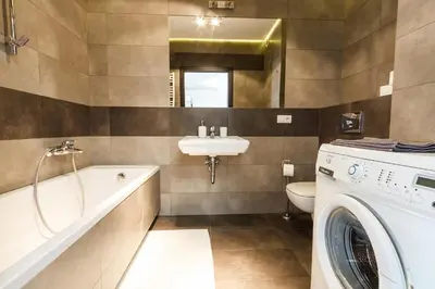 a bathroom with a washing machine and a sink at Apartamenty Lea in Kraków