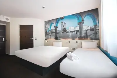 two beds in a room with a painting on the wall at B&B HOTEL Krakow Centrum in Kraków