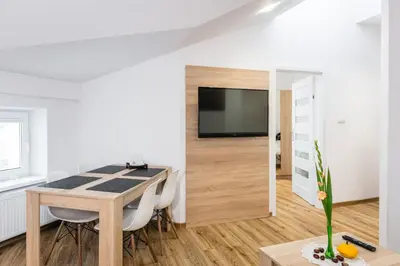 a dining room with a table and a tv at Apartamenty Bosacka WAWELOFTS in Kraków
