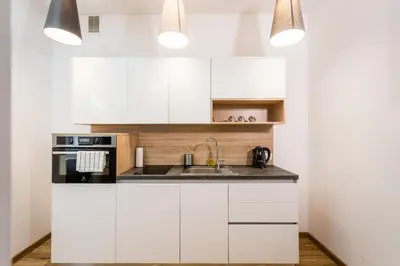 a kitchen with white cabinets and a sink at Apartamenty Bosacka WAWELOFTS in Kraków