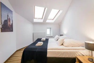 a white bedroom with a large bed with skylights at Apartamenty Bosacka WAWELOFTS in Kraków