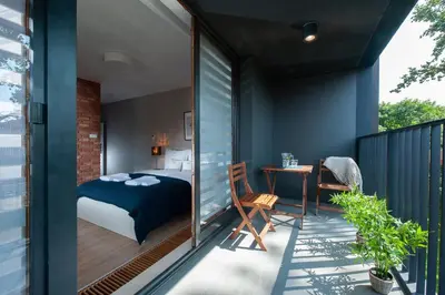 a bedroom with a bed and a table on a balcony at Browar Lubicz Residence in Kraków