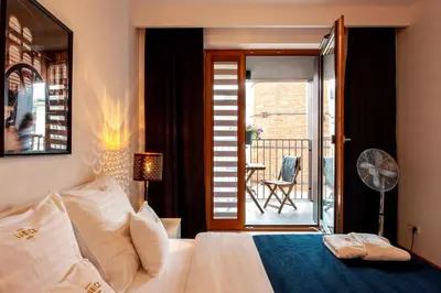 a bedroom with a bed and a balcony with a chair at Browar Lubicz Residence in Kraków