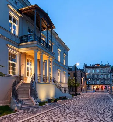 a large building with stairs on a cobblestone street at Browar Lubicz Residence in Kraków