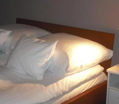 a bed with white sheets and pillows on it at Apartamenty Algador in Kraków