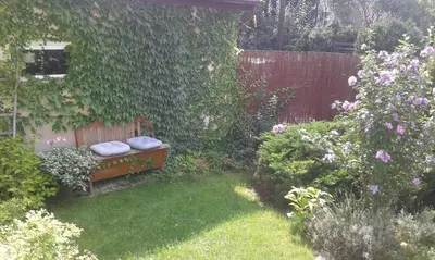 a garden with a bench with two pillows on it at Apartamenty Algador in Kraków