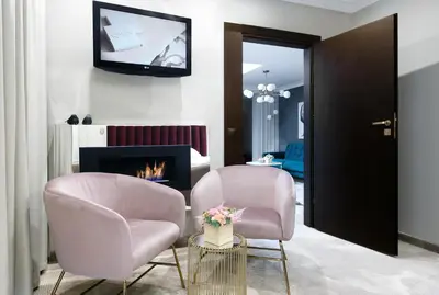 a living room with two chairs and a fireplace at Queen Boutique Hotel in Kraków