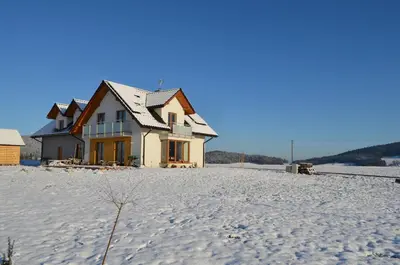 a house in the middle of a snow covered field at Pokoje na Wzgórzu in Kasina Wielka