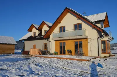 a house in the winter with snow on the ground at Pokoje na Wzgórzu in Kasina Wielka