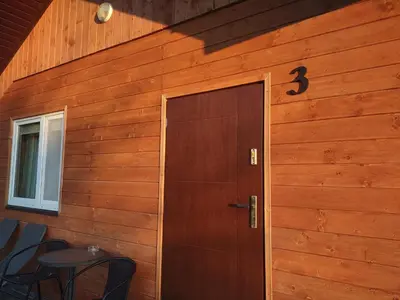 a door in a wooden wall with a table next to it at Idylla in Połom Mały