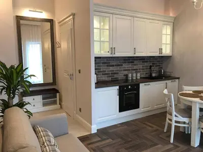 a kitchen with white cabinets and a living room with a table at Apartament w centrum Krakowa Ariańska 6 in Kraków