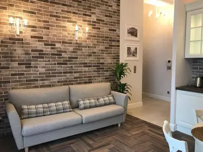 a couch in a living room with a brick wall at Apartament w centrum Krakowa Ariańska 6 in Kraków