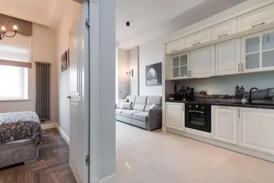 a kitchen with white cabinets and a living room with a couch at Apartament w centrum Krakowa Ariańska 4 in Kraków