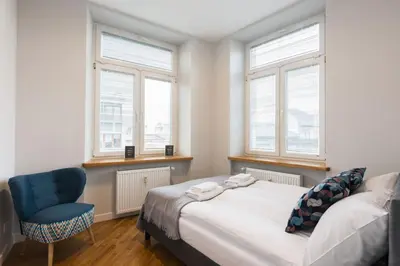 a bedroom with a bed and a chair and windows at Luxury Apartments Nearto Main Square in Kraków