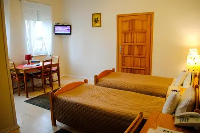 a room with two beds and a table and a door at Hotel Krak in Myślenice
