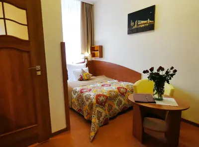 a bedroom with a bed and a table with a vase of flowers at Aparthotel Adler in Kraków