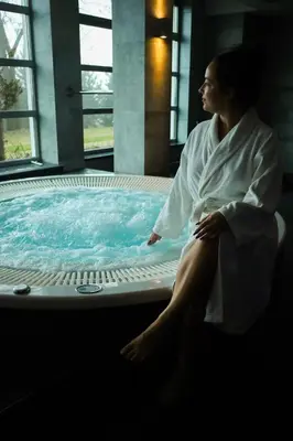 a woman sitting in front of a hot tub at Radocza Park Active & Spa in Radocza