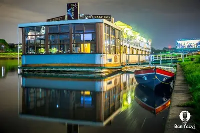 a building on a river with a boat in the water at The Boat - Hostel&Chill in Kraków