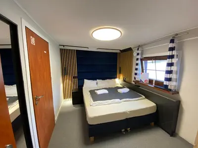 a small bedroom with a bed with a blue headboard at The Boat - Hostel&Chill in Kraków