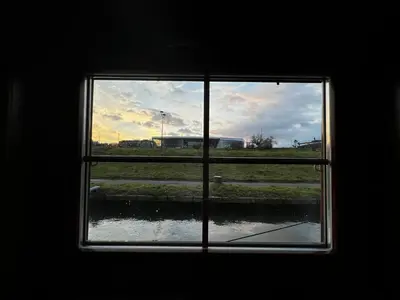 a window with a view of a field seen through it at The Boat - Hostel&Chill in Kraków