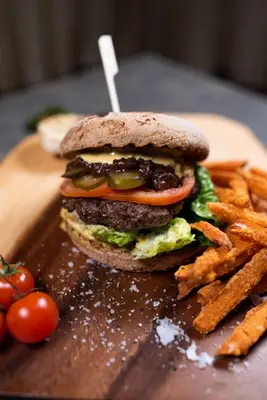 a hamburger and french fries on a wooden plate at Hotel-Restauracja Platan in Chrzanów