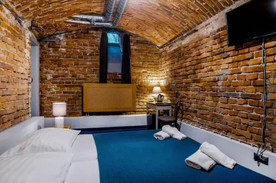 a brick walled bedroom with a bed and a tv at Apartamenty Bluma in Kraków