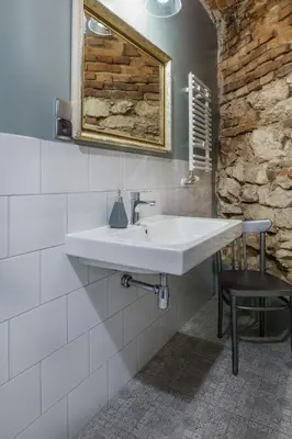 a bathroom with a white sink and a black stool at Apartamenty Bluma in Kraków