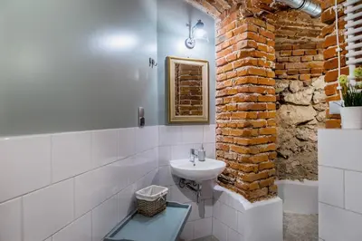a bathroom with a sink and a brick wall at Apartamenty Bluma in Kraków