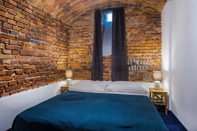 a bedroom with a brick wall and a blue bed at Apartamenty Bluma in Kraków