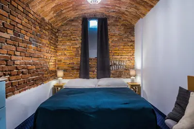 a brick walled bedroom with a bed and two windows at Apartamenty Bluma in Kraków