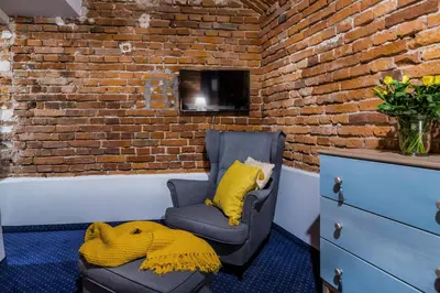 a chair with a yellow blanket sitting next to a brick wall at Apartamenty Bluma in Kraków